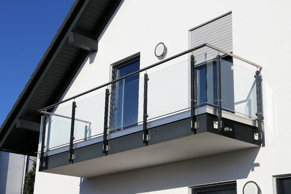 Balkon mit Glasgeländer an einer weißen Hauswand